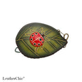 A small leaf-shaped leather pouch with a ladybug applique on a green leaf design, shown on a white background with the LeatherChic brand name at the bottom.