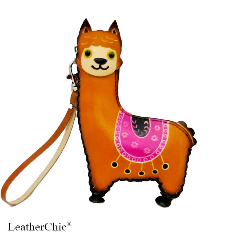 An orange alpaca-shaped leather wristlet wallet with a matching wrist strap, featuring a pink patterned saddle design on its back, set against a plain white background.