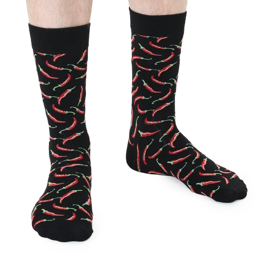 Black socks with red chili pepper pattern worn by a person on a white background
