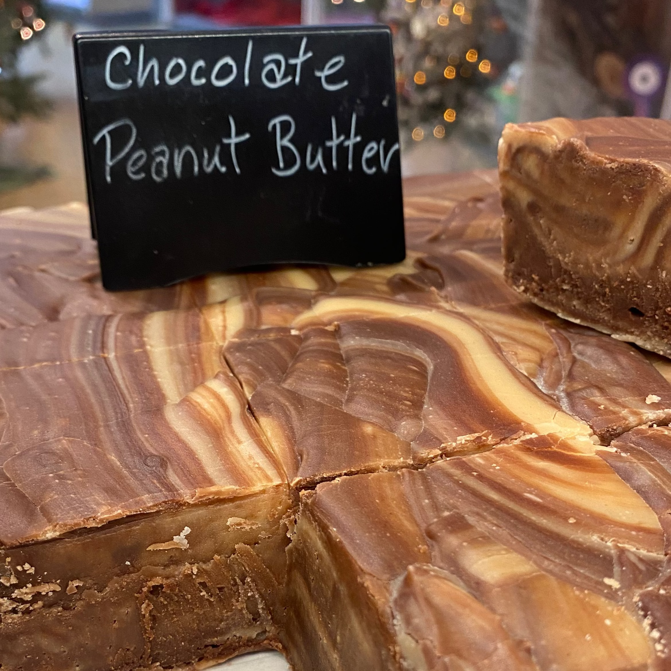 Chocolate Peanut Butter fudge with a piece cut out, displayed on a marble surface.