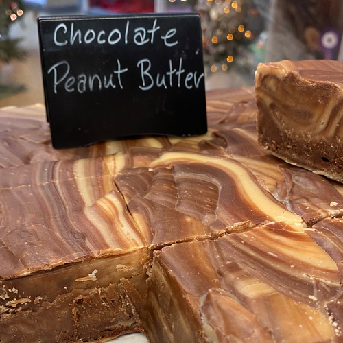 Chocolate Peanut Butter fudge with a piece cut out, displayed on a marble surface.