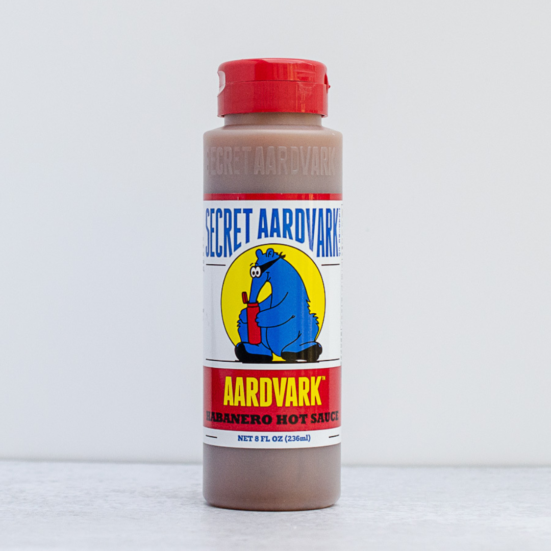 Bottle of Secret Aardvark hot sauce with a red cap on a white background