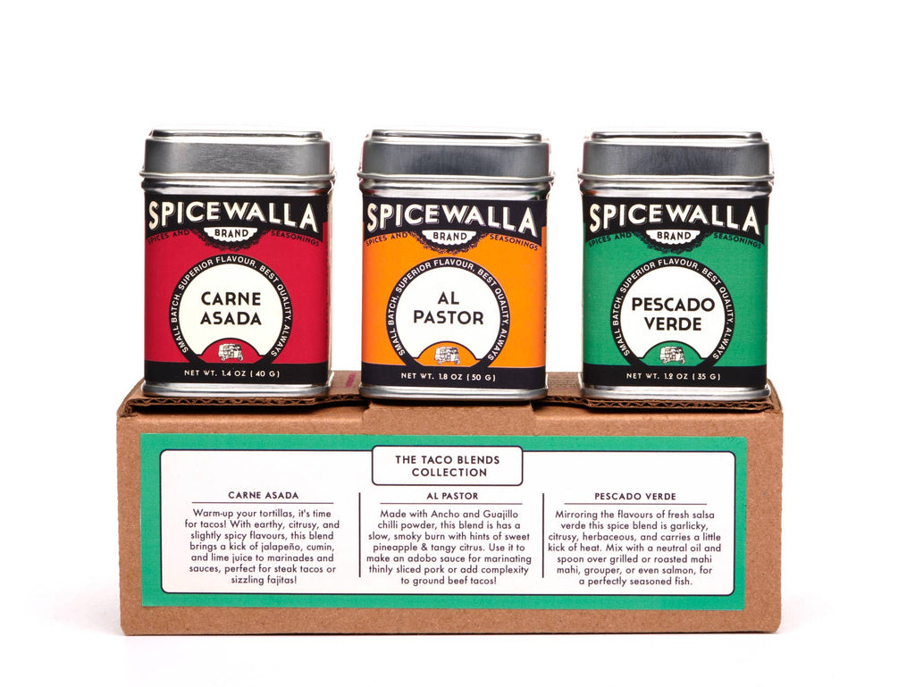 Three Spicewalla spice tins in red, orange, and green on a cardboard stand with labels.