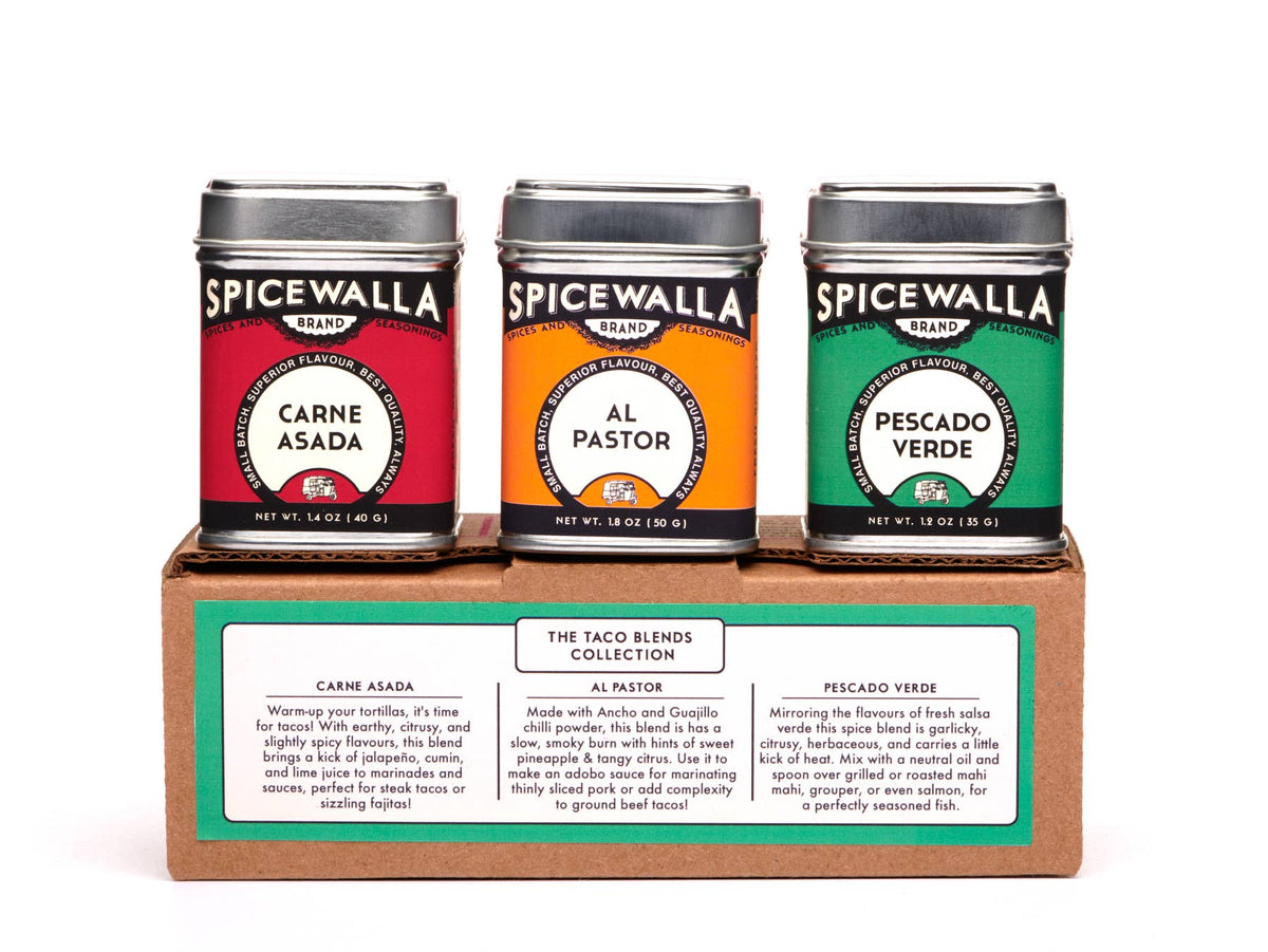 Three Spicewalla spice tins in red, orange, and green on a cardboard stand with labels.