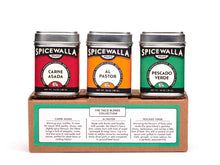 Load image into Gallery viewer, Three Spicewalla spice tins in red, orange, and green on a cardboard stand with labels.
