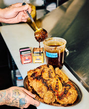 Load image into Gallery viewer, Fried chicken being drizzled with a dark sauce on a metal tray.
