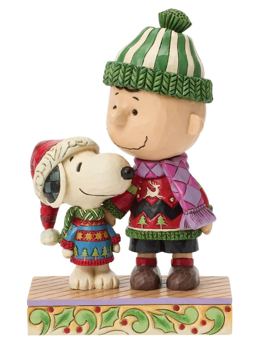 A decorative figurine of Charlie Brown and Snoopy wearing festive Christmas sweaters and hats, standing together on a patterned base against a plain white background.