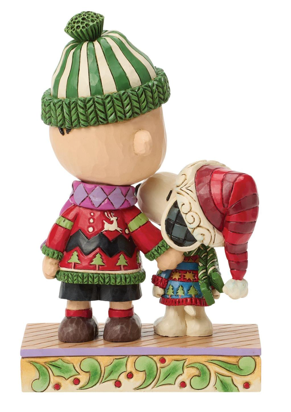 A decorative figurine of Charlie Brown and Snoopy dressed in holiday winter clothing, standing together on a patterned base against a plain white background.