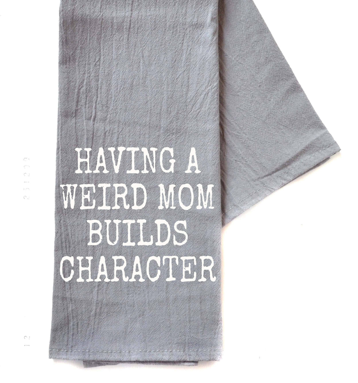 Gray towel with white text 'HAVING A WEIRD MOM BUILDS CHARACTER' on a white background