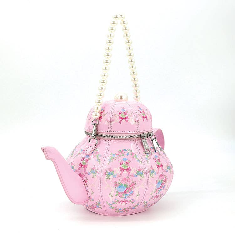 Pink teapot-shaped handbag with floral patterns on a white background