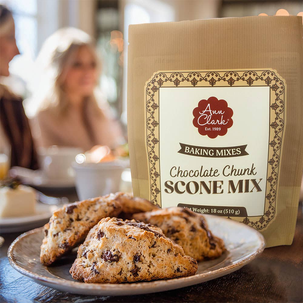Bag of Ann Clark Chocolate Chunk Scone Mix with scones on a plate in a blurred cafe setting
