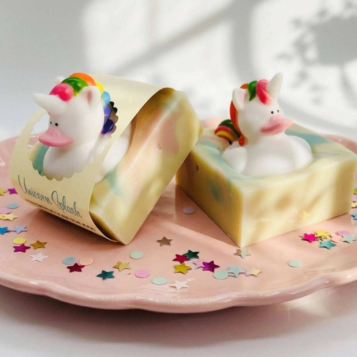 Unicorn-shaped soap with a packaging labeled 'Unicorn Island' on a pink plate with star-shaped confetti.