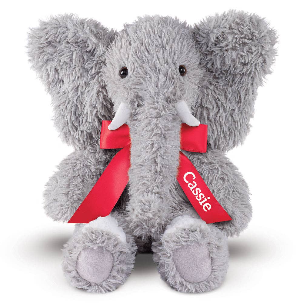 Gray plush elephant with red ribbon and 'Cassie' tag on a white background