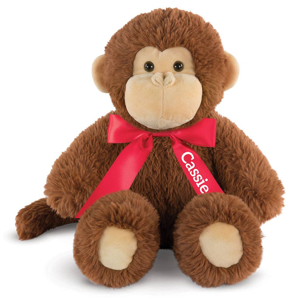 Plush monkey toy with a red bow and 'Cassie' tag on a white background