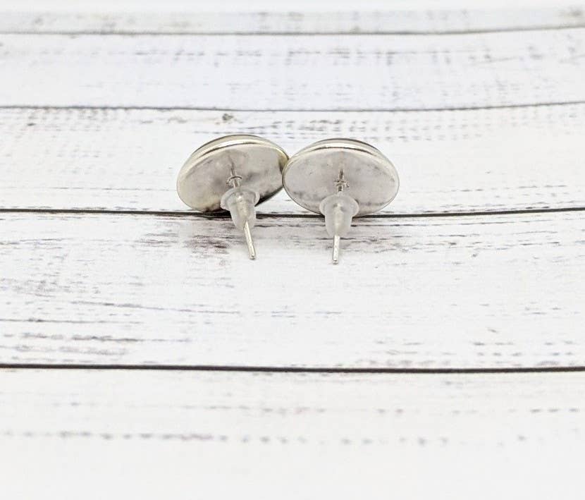 Pair of silver stud earrings on a white wooden surface
