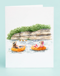 Illustration of two people on inflatable rings in a lake with trees and rocks in the background.