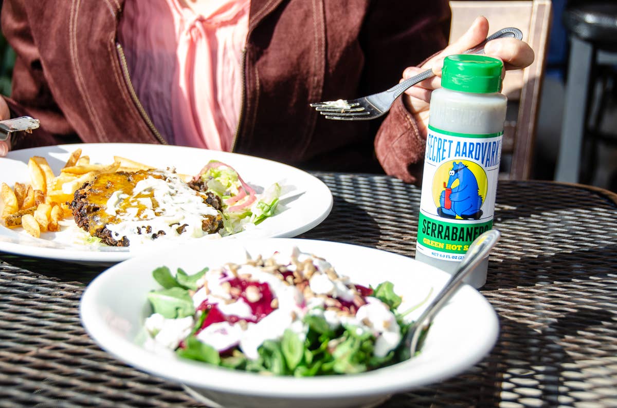 Two plates of food on a table with a bottle of Berrabam margarine.